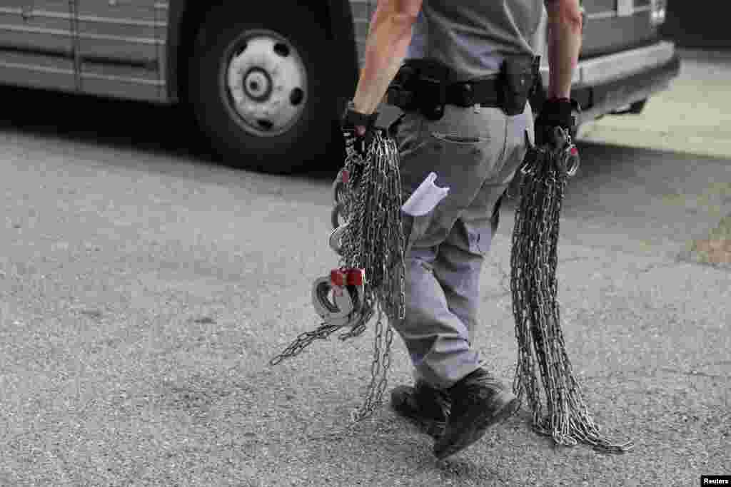 텍사스 남부 매캘런의 미 연방 법원 밖에서 경찰이 미등록 이민자들에게 채우는 수갑을 들고 걷고 있다.