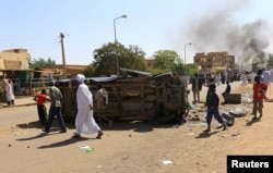 FILE - A police car flipped over and damaged by mourners is seen near the home of a demonstrator who died of a gunshot wound sustained during anti-government protests in Khartoum, Sudan, Jan. 18, 2019.