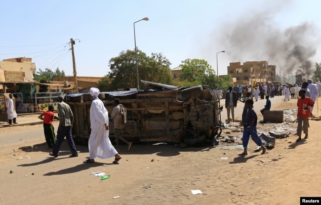 FILE - A police car flipped over and damaged by mourners is seen near the home of a demonstrator who died of a gunshot wound sustained during anti-government protests in Khartoum, Sudan, Jan. 18, 2019.