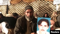 FILE - Mohammad Bilal holds a picture of his son Hazratullah as he takes part in a protest with members of the Pashtun community against what they say are enforced “disappearances” and routine oppression, in Islamabad, Feb. 8, 2018. 