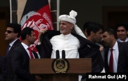 阿富汗总统加尼在总统府发表就职演说期间在有人发射了几枚火箭后解开大衣。(2020年3月10日)
