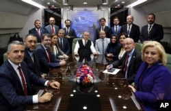 Turkey's President Recep Tayyip Erdogan, center, poses inside his plane for a photo with journalists traveling with him back from a state visit to Hungary, late Wednesday, Oct. 10, 2018. Erdogan has increased his pressure on Saudi Arabia over the disappearance of journalist Jamal Khashoggi.