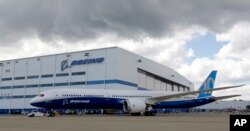 FILE - Boeing employees stand near the new Boeing 787-10 Dreamliner at the company's facility in South Carolina after conducting its first test flight at Charleston International Airport in North Charleston, S.C., March 31, 2017.
