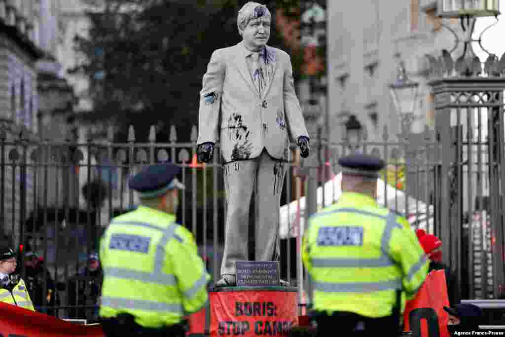 Police officers stand guard as Greenpeace activists stage a sit-in after installing an oil-splattered statue of British Prime Minister Boris Johnson by artist Hugo Farmer at Downing Street in London&nbsp; during a protest against the Cambo oil field project in the Shetland Islands.
