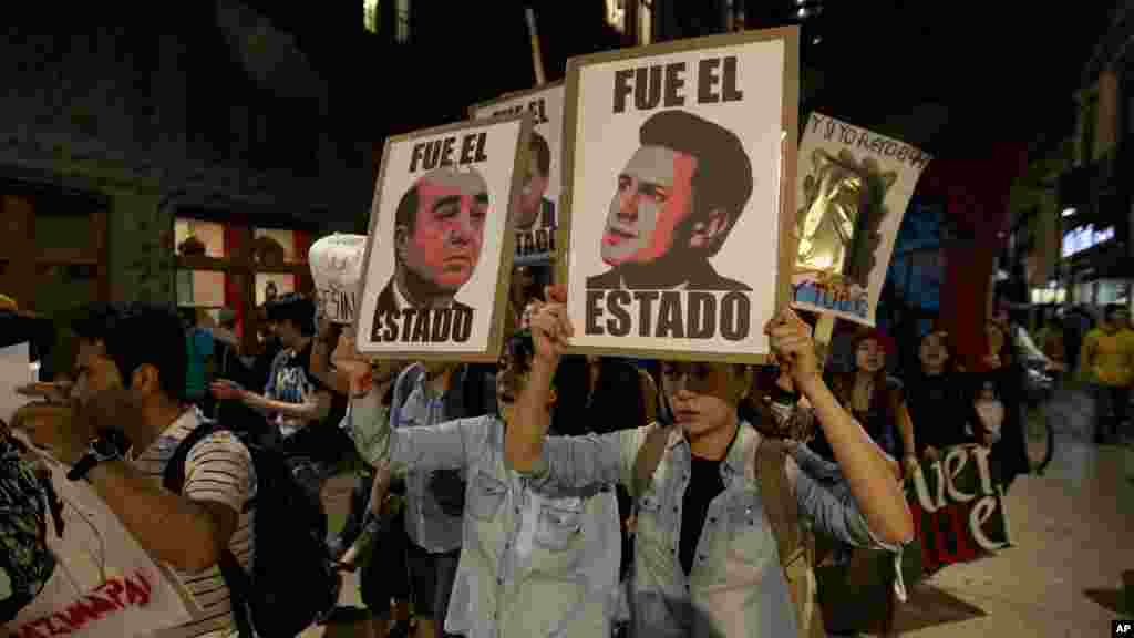 Demonstrators holding posters of Mexico's President Enrique Pena Nieto, right, and Attorney General, Jesus Murillo Karam, left, march in protest for the disappearance of 43 students in the state of Guerrero, in Mexico City, Nov. 5, 2014. 