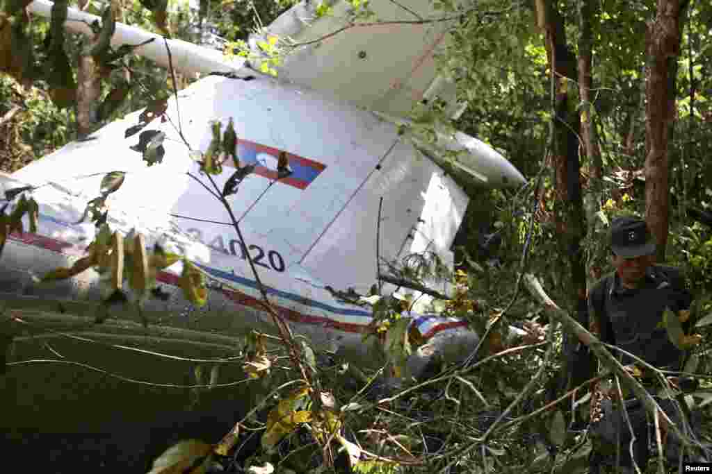 A rescue worker makes his way past the wreckage of an air force plane at its crash site near Nadee village, in Xiang Khouang province, Laos, May 17, 2014.