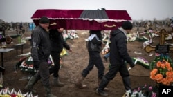 Ukrainian municipal workers carry a coffin bearing the body of Vitaliy Sirotenko, who was killed Saturday during an attack in Mariupol, Ukraine, on Jan. 27, 2015. 