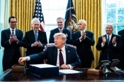 Treasury Secretary Steven Mnuchin, left, Vice President Mike Pence, second from right, and Republican lawmakers applaud President Donald Trump during a signing ceremony of a $2.2 trillion stimulus measure, at the White House, in Washington, March 27, 2020.