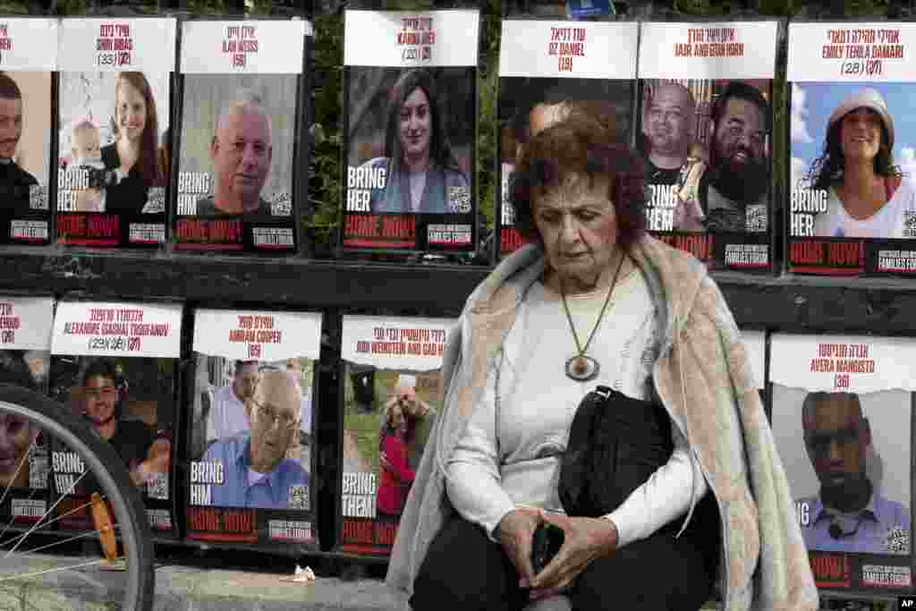 A woman pauses near posters of hostages held by Hamas in the Gaza Strip, in Tel Aviv, Israel.