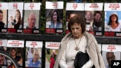 A woman pauses near posters of hostages held by Hamas in the Gaza Strip, in Tel Aviv, Israel.