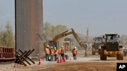 ARCHIVO - Contratistas del gobierno levantan una sección del muro fronterizo financiado por el Pentágono a lo largo del río Colorado, el 10 de septiembre de 2019, en Yuma, Arizona.