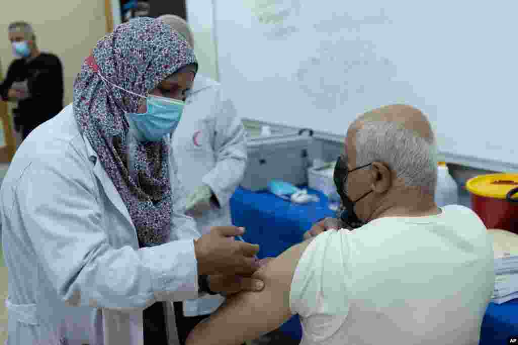 یک معلم فلسطینی واکسن کرونای ساخت آکسفورد – آسترازنکا را در رام‌الله در کرانه باختری دریافت می‌کند.