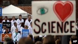 FILE - People hold signs as they listen to a group of scientists speak during a rally in conjunction with the American Geophysical Union's fall meeting Dec. 13, 2016, in San Francisco. The rally was to call attention to the issue of climate change and its