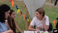 La primera dama de Ucrania, Olena Zelenska, habla con una niña durante su visita al campamento de rehabilitación infantil para afectados por la guerra, en Uzhgorod, Ucrania, el 27 de agosto de 2024.