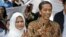Indonesian presidential candidate Joko Widodo, popularly known as "Jokowi", left, and his wife Iriana, show their inked fingers after casting their ballots during the presidential election in Jakarta, Indonesia, July 9, 2014. 