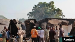 Residents gather behind destroyed structures after gunmen attacked Mpeketoni, Kenya, June 16, 2014. 