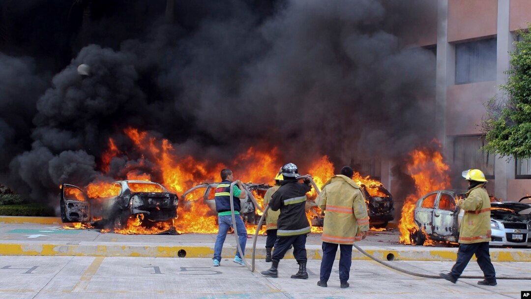 Firefighters try to extinguish burning vehicles in front of the state congress building after protesting teachers torched them in the state capital city of Chilpancingo, Mexico, Nov. 12, 2014. 