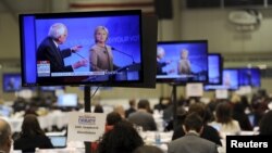 US Democratic presidential candidates Hillary Clinton and Bernie Sanders appear on television screens in the media work-room during the Democratic presidential candidates debate.