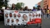 Protesters hold a banner featuring resigned Gov. Ricardo Rosselló, center, amid other politicians that reads "The 12 disciples of evil. Them too." as they demand the resignation of Justice Secretary Wanda Vazquez in San Juan, Puerto Rico, July 29, 2019.