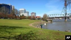 FILE - A man walks along a pathway beside the Willamette River in Portland, Oregon, March 17, 2016. 