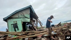 A man makes his way past a house badly damaged by a tsunami in Sumur, Indonesia, Dec. 24, 2018. 