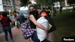 Un migrante venezolano con mascarilla sostiene una bolsa de ayuda alimentaria donada por el gobierno interino del país en Bogotá, Colombia. Mayo 29, 2020.