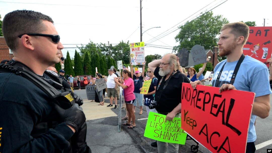 Watched by police, demonstrators against the Senate Republican health care bill await the arrival of Pennsylvania's U.S. Sen. Pat Toomey outside the studios of WHTM-TV, July 5, 2017 in Harrisburg, Pa.