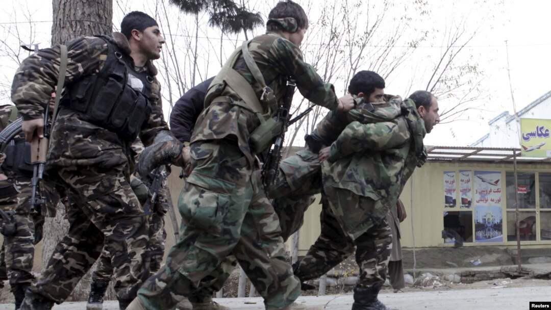 Pasukan keamanan Afghanistan menggendong rekannya yang terluka dalam baku tembak melawan kawanan bersenjata di Mazar-i-Sharif, Afghanistan, Senin (4/1).