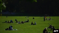 People sit in the grass at Central Park on October 15, 2020 in New York City. (Photo by Angela Weiss / AFP)