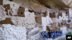 FILE - In this Aug. 27, 2005 photo, visitors tour Cliff Palace, an ancient cliff dwelling in Mesa Verde National Park, Colorado.