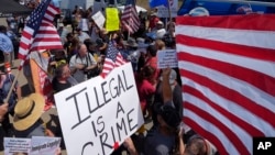 FILE - Demonstrators confront each other, Friday, July 4, 2014, outside a U.S. Border Patrol station in Murrieta, Calif. Demonstrators on both sides of the immigration debate had gathered where the agency was foiled earlier this week in an attempt to bus in and process some of the immigrants who have flooded the Texas border with Mexico. (AP Photo/Mark J. Terrill)