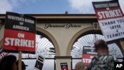 FILE - Demonstrators walk with signs during a rally outside the Paramount Pictures Studio in Los Angeles, Thursday, Sept. 21, 2023. A tentative deal was reached, Sunday, Sept. 24, 2023, to end Hollywood’s writers strike after nearly five months. 