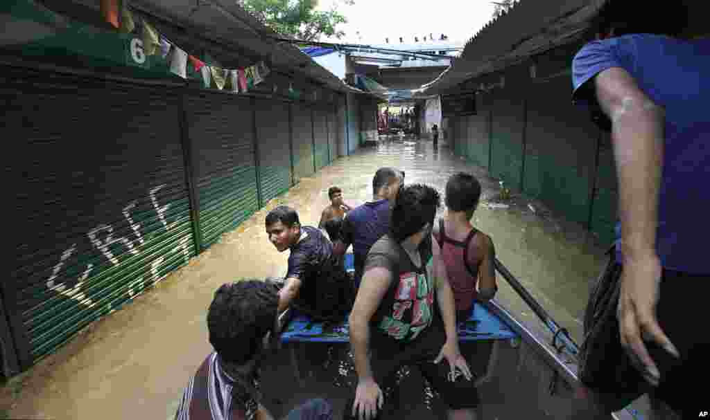 People use a boat to cross a market along the banks of the Yamuna River, in New Delhi, India, June 19, 2013. 