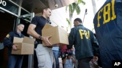 Petugas Biro Penyelidik Federal AS (FBI) mengumpulkan barang bukti skandal korupsi FIFA dari markas Konfederasi Asosiasi Sepak Bola Amerika Utara, Amerika Tengah dan Karibia (CONCACAF) di Miami Beach, Florida (27/5).