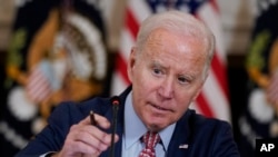 U.S. President Joe Biden adjusts his microphone during a meeting with the President's Council of Advisors on Science and Technology in the State Dining Room of the White House, April 4, 2023, in Washington. 