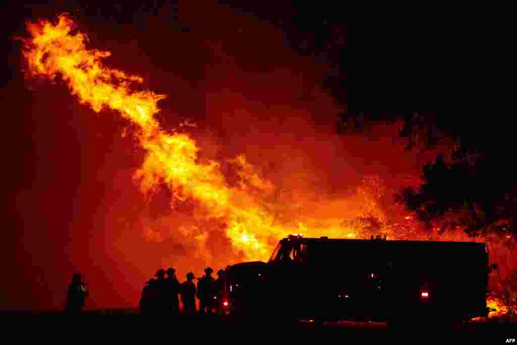 Butte county firefighters watch as flames tower over their truck at the Bear fire in Oroville, California.