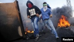 Palestinian protesters run for cover during clashes with Israeli troops near the Jewish settlement of Beit El, near the West Bank city of Ramallah, Oct. 9, 2015. 