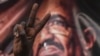 (FILES) In this file photo taken on April 19, 2019, a Sudanese protester flashes a victory sign in front of a banner depicting ousted and detained president Omar al-Bashir, during a protest outside the army headquarters in the capital Khartoum. - A…