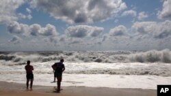 Beachgoers stand at the edge of the water in Bridgehampton, N.Y, Sunday, Sept. 4, 2016.