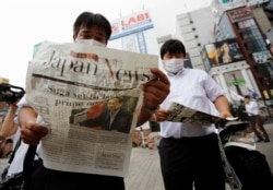 Men read extra editions of a newspaper reporting Japanese Chief Cabinet Secretary Yoshihide Suga won in a ruling party leadership election paving the way for him to replace Prime Minister Shinzo Abe in Tokyo