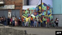 Venezuelan citizens wait for a public transportation at a bus stop in Caracas, Venezuela, Jan. 3, 2018.