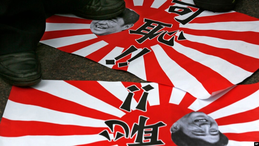 Poster anti-Jepang bergambarkan PM Shinzo Ane dan bendera militer Jepang nampak diinjak-injak masa dalam protes di Hong Kong (15/8). Ziarah dua menteri Jepang ke Yasukuni untuk menghormati tentara perang Jepang, kembali memicu kemarahan Korea Selatan dan Cina, dua dari korban agresi Jepang dalam paruh pertama abad ke-20.