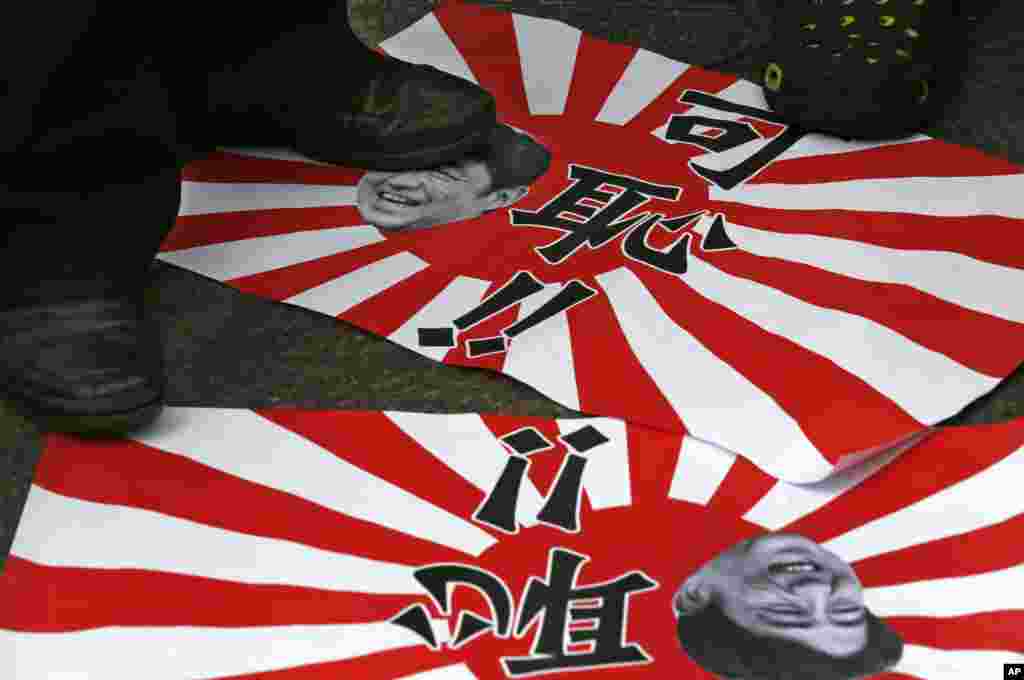 Anti-Japan protesters step on Japanese military flags featuring picture of Japanese Prime Minister Shinzo Abe and Chinese words, " Shame " in Hong Kong, August 15, 2013. 