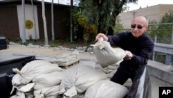 Frank Salazar, de Glendora, California, prepara bolsas de arena para proteger su vivienda de las posibles inundaciones que se prevén en los próximos días.