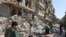 People remove belongings from a damaged site after an air strike Sunday in the rebel-held besieged al-Qaterji neighbourhood of Aleppo, Syria, Oct. 17, 2016. 