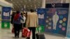 FILE - Travelers pass by a health checkpoint before entering immigration at the international airport in Beijing, Jan. 13, 2020.