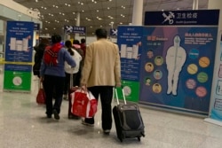 FILE - Travelers pass by a health checkpoint before entering immigration at the international airport in Beijing, Jan. 13, 2020.