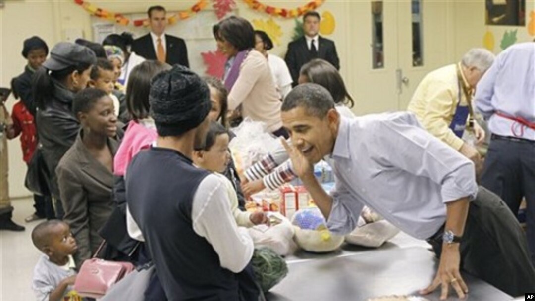President Barack Obama leans over to listens to hear a child speak as he helps pack food for Thanksgiving at Martha's Table, a local food pantry in Washington, 24 Nov., 2010