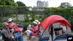 Supporters of President Donald Trump, from left, James DeWilde, Laureen Vartanian and Maureen Bailey wait in line with others on Monday, June 17, 2019, in Orlando, Fla. 