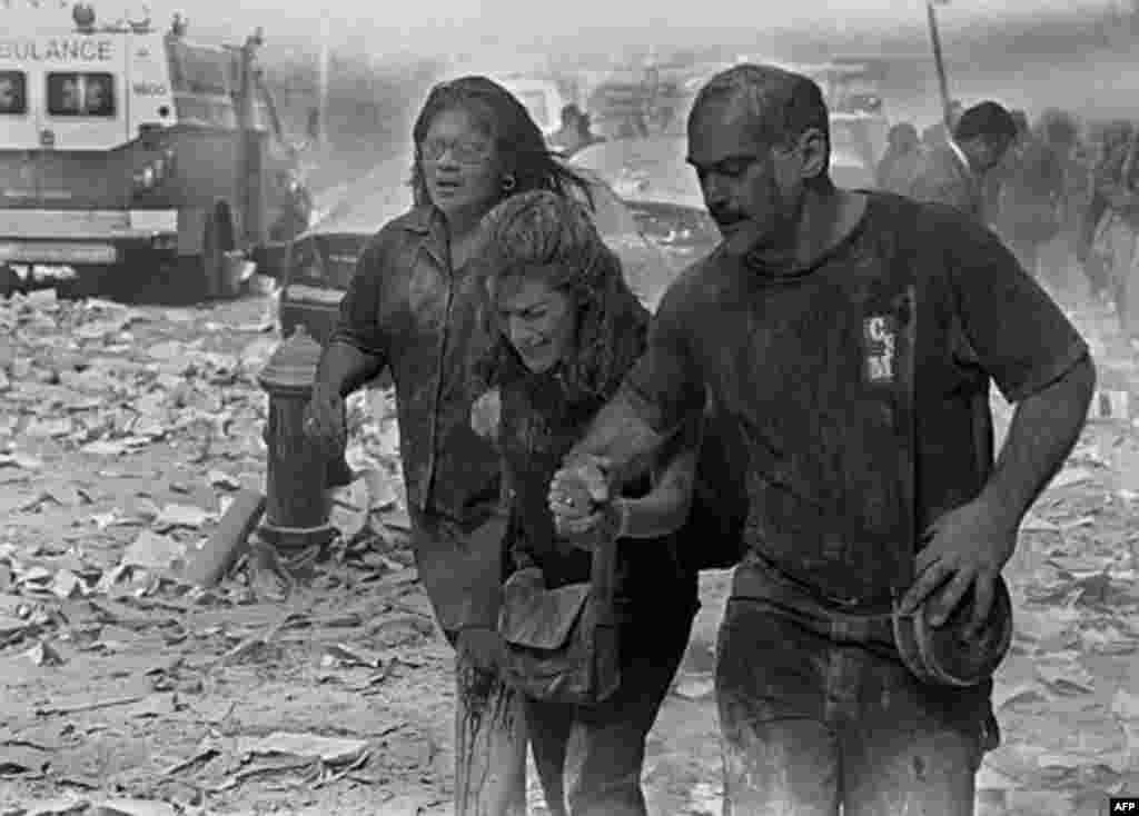 Julie McDermott, center, walks with other victims as they make their way amid debris near the World Trade Center in New York Tuesday Sept. 11, 2001. In one of the most horrifying attacks ever against the United States, terrorists crashed two airliners int